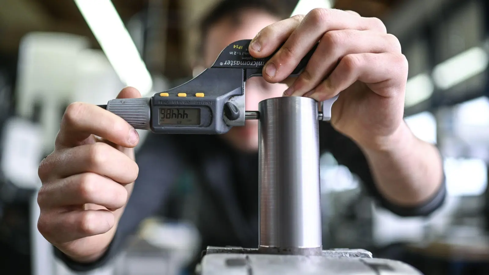 Ein Auszubildender im Metall-Handwerk misst in einem Ausbildungszentrum die Dicke eines Werkstücks. (Foto: Felix Kästle/dpa)