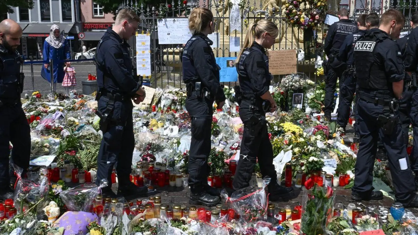 Polizisten stehen auf dem Marktplatz vor einem Gedenkplatz für einen bei einer Messerattacke getöteten Polizisten. (Foto: Bernd Weißbrod/dpa)