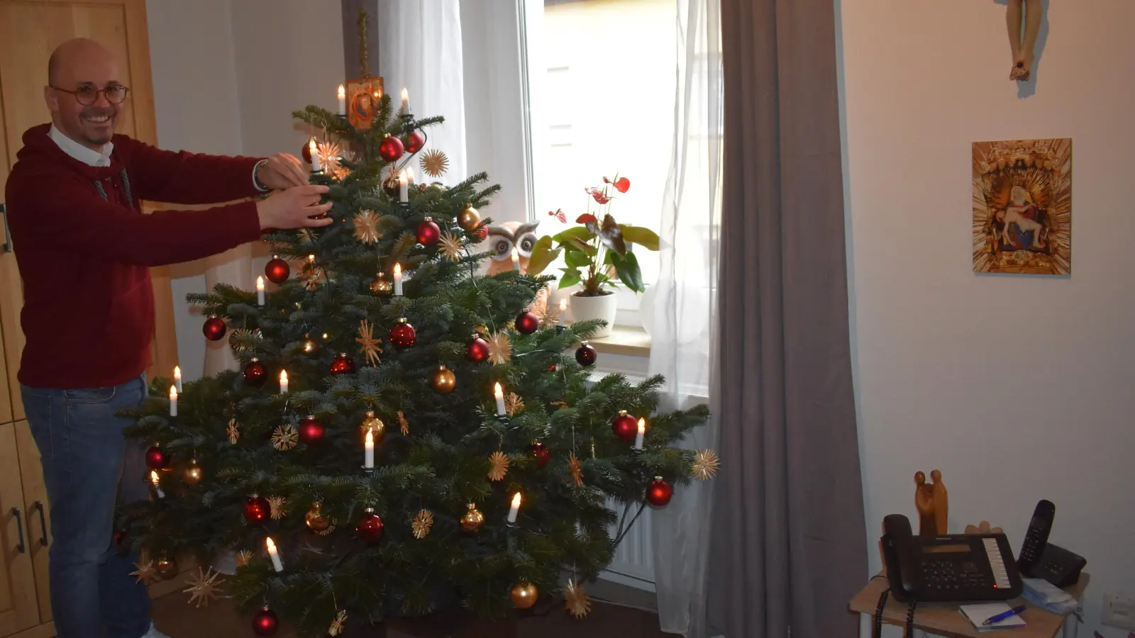 Pfarradministrator Daniel Bittel mag beim Christbaumschmuck ganz klassische Farbenkombinationen wie Rot und Gold. (Foto: Ute Niephaus)