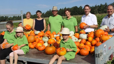 Start der Kürbissaison mit Julia Ploch, Projekt Heimkommen LAG Region an der Romantischen Straße; Andrea Denzinger, Regionalmanagement des Landkreises Ansbach; Jörg und Michaela Uysmüller, Kürbisproduzenten; Dr. Jürgen Ludwig, Landrat des Landkreises Ansbach und Walter Soldner, zweiter Bürgermeister Stadt Feuchtwangen (von links). Vorne auf dem Wagen sitzen die Kinder der Uysmüllers. (Foto: Daniela Ramsauer)