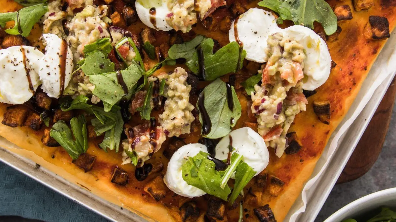 Wie ein Gemälde: Pizza vom Blech mit Süßkartoffel, Büffelmozzarella, Guacamole, Rucola, Balsamico. (Foto: Christin Klose/dpa-tmn/dpa)