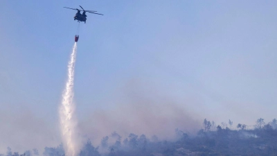 Ein Hubschrauber wirft Wasser auf einen Waldbrand im Norden Athens ab. (Foto: Yorgos Karahalis/AP)
