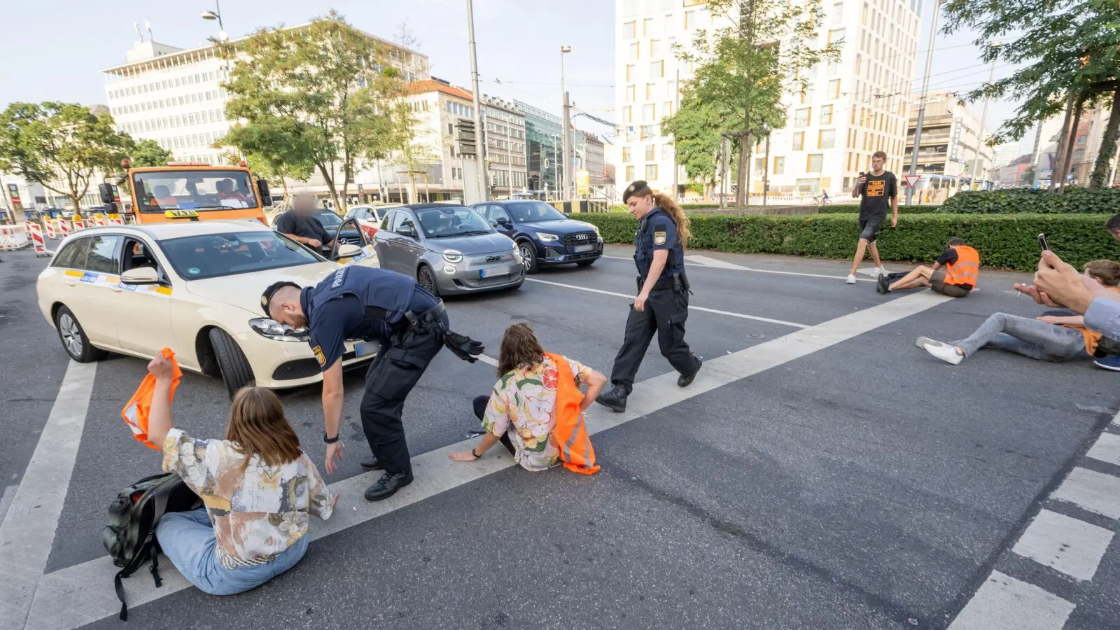 Polizisten und Aktivisten der Letzten Generation, die sich zuvor auf der Straße festgeklebt haben. (Foto: Peter Kneffel/dpa)