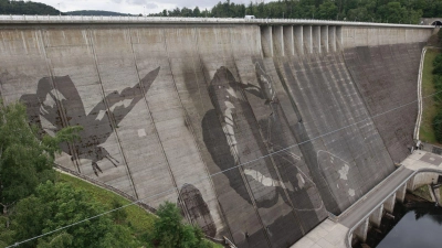 Auf der Staumauer der größten Trinkwassertalsperre Deutschlands wird mit Hochdruckreinigern ein Kunstwerk gemalt. (Foto: Matthias Bein/dpa)