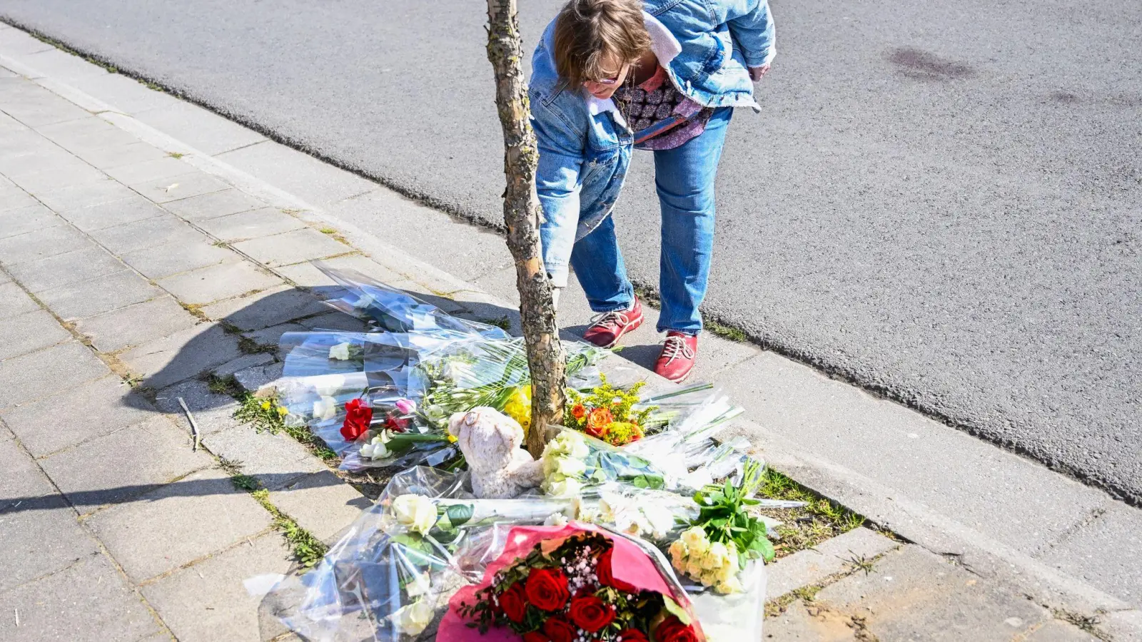 Eine Frau im belgischen La Louviere legt Blumen an der Unfallstelle nieder, wo ein angetrunkener Autofahrer bei einer Karnevalsveranstaltung in eine Menschengruppe gefahren ist. Sechs Menschen starben, zehn waren am Montag noch in kritischem Zustand. (Foto: Laurie Dieffembacq/BELGA/dpa)