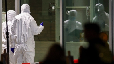 Polizeibeamte der Spurensicherung in weißen Schutzanzügen untersuchen Löcher in Glasscheiben des Kinos. (Foto: Christoph Reichwein/dpa)