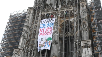Klimaaktivisten haben am Ulmer Münster mit dem höchsten Kirchturm der Welt ein Protestbannner entrollt. (Foto: Ralf Zwiebler/dpa)