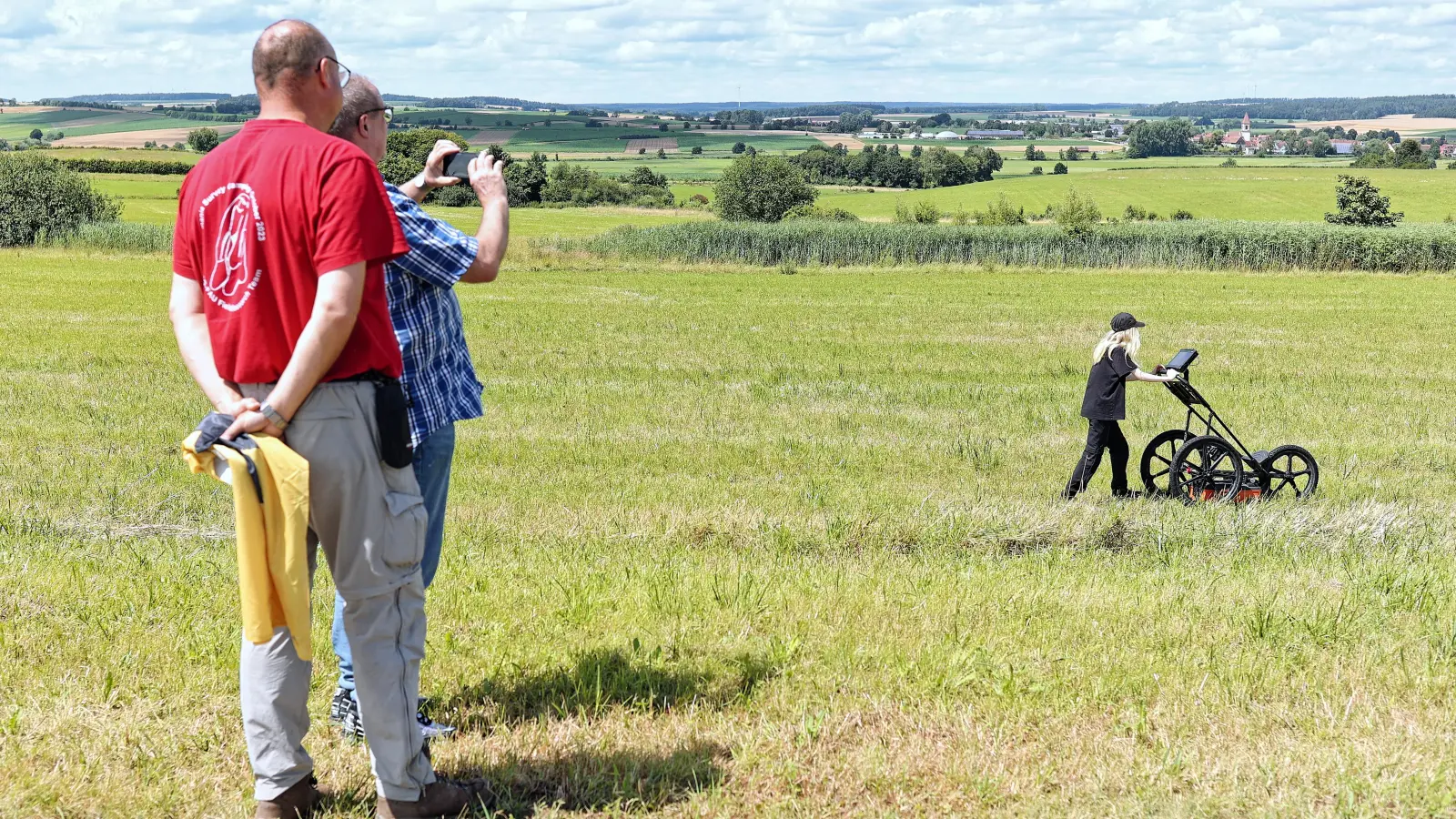 Dr. Carsten Mischka und Dr. Matthias Pausch (von links) beobachten aus der Ferne die Studentin Hannah Zeh bei einer Messung mit dem Radargerät auf der Fläche rund um das Limeseum-Gebäude. (Foto: Tizian Gerbing)