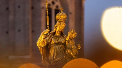 Eine goldene Marienfigur steht auf dem Marienplatz in München im Licht des umliegenden Weihnachtsmarkts. (Foto: Peter Kneffel/dpa)