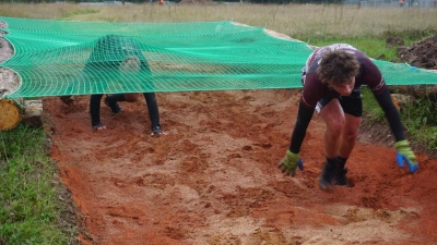 Krabbel-Übung auf dem Parcours: Unter einem Netz hindurch und durch den Schlamm mussten die Teilnehmenden beim Mud Run. (Foto: Paul Wiese)