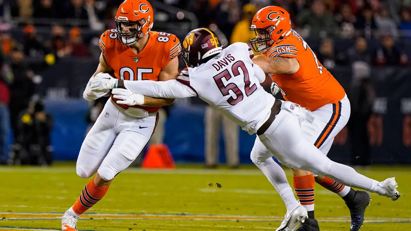 Chicagos Tight End Cole Kmet (l) wird von Washingtons Linebacker Jamin Davis (M) angegangen. (Foto: Nam Y. Huh/AP/dpa)