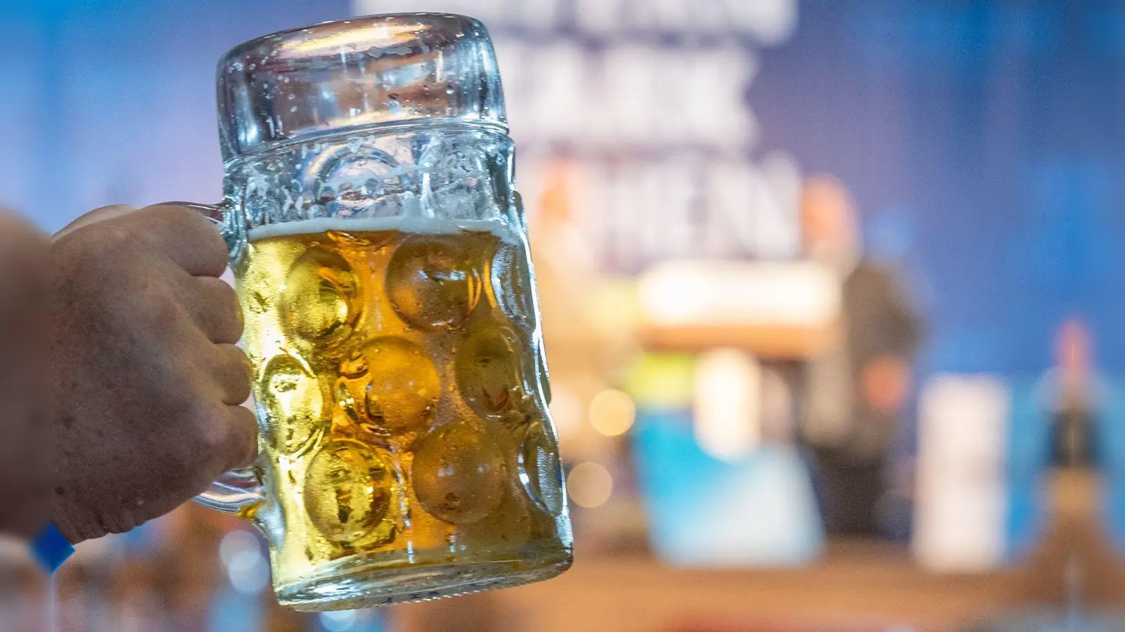 Ein Mann hält eine Maß Bier hoch. (Foto: Armin Weigel/dpa/Symbolbild)