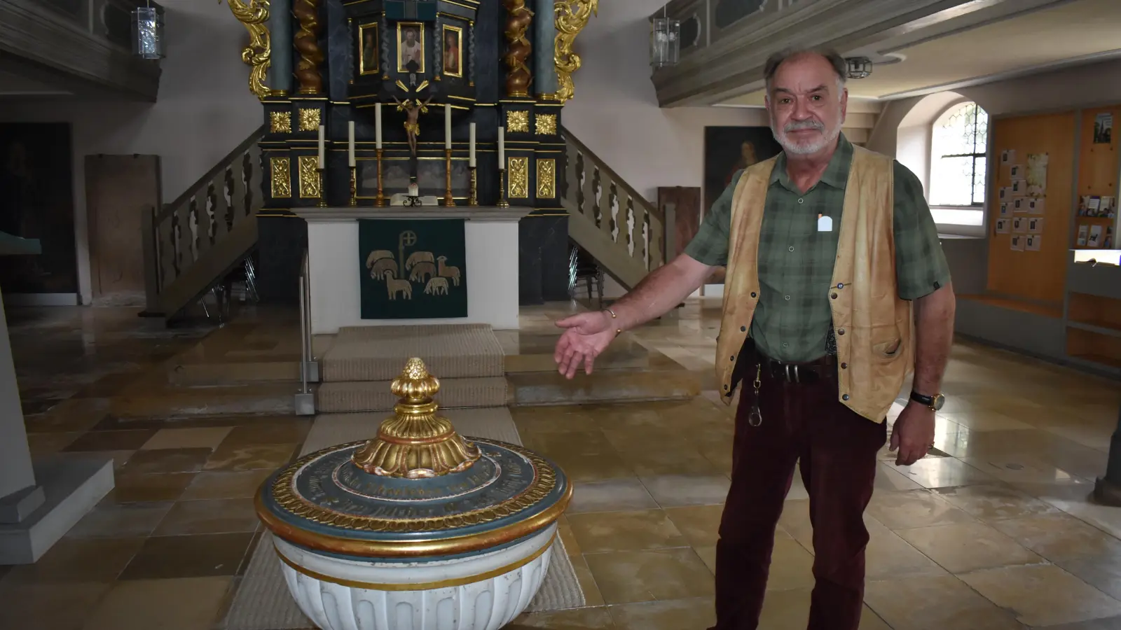 Bernd-Valentin Schuler darf sich nach seiner Ausbildung und der bestandenen Prüfung qualifizierter Kirchenführer nennen. Er zeigt Interessierten gern die Emskirchener Kirche. Hier sind zum Beispiel der Taufstein und im Hintergrund der Kanzelaltar zu sehen. (Foto: Ute Niephaus)