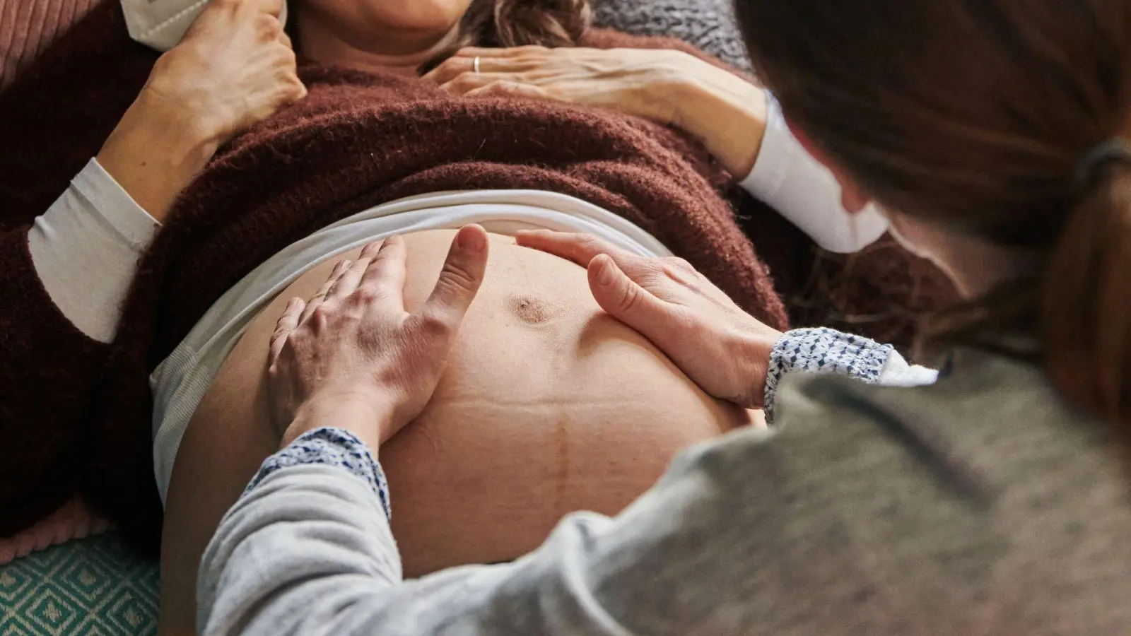 Eine Hebamme tastet in ihrer Praxis den Bauch einer schwangeren Frau ab. (Archivbild) (Foto: Annette Riedl/dpa)