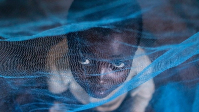 Ein Flüchtlingskind aus Burundi sitzt in Gashora, Ruanda, unter einem Moskitonetz: Der Malaria-Erreger wird durch Anopheles-Stechmücken übertragen. (Foto: Dai Kurokawa/EPA/dpa)