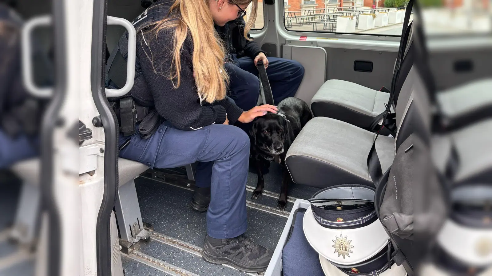 Eine Bundespolizistin kümmert sich nach der S-Bahnfahrt der entlaufenen „Chicka“ im Polizeibus um die Hündin. (Foto: -/Bundespolizeiinspektion München/dpa)