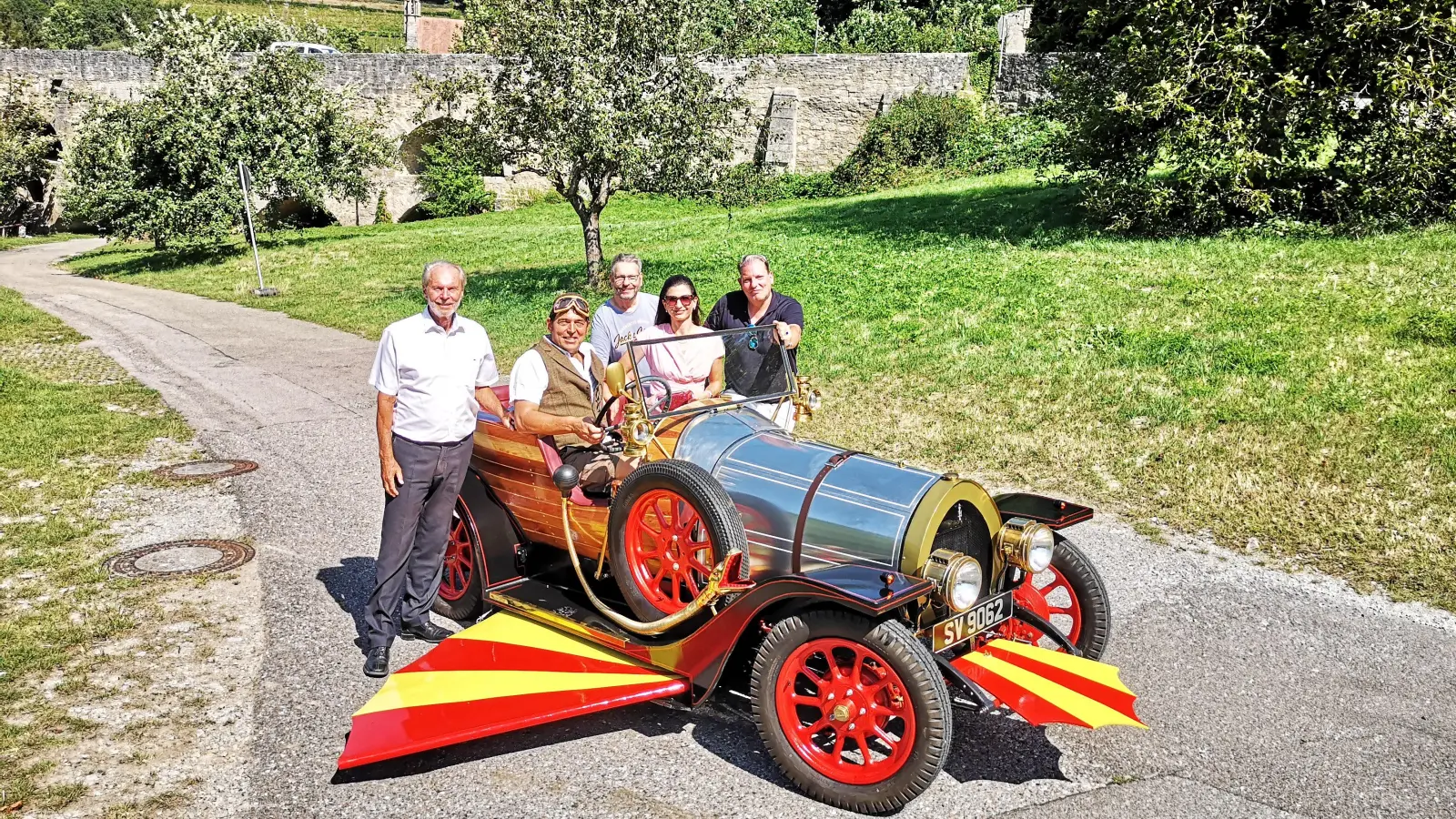 Die Doppelbrücke war 1967 Drehort für „Tschitti Tschitti Bäng Bäng“. Dort parkte Tim Preece (Zweiter von links) am Samstag den Nachbau des Film-Oldtimers. Richard Zoll (Mitte), zweiter Bürgermeister Dieter Kölle (links), Mediroth-Vorsitzende Michaela Ebner und Schnauferl-Club-Vertreter Benjamin Babel waren dabei. (Foto: Jürgen Binder)