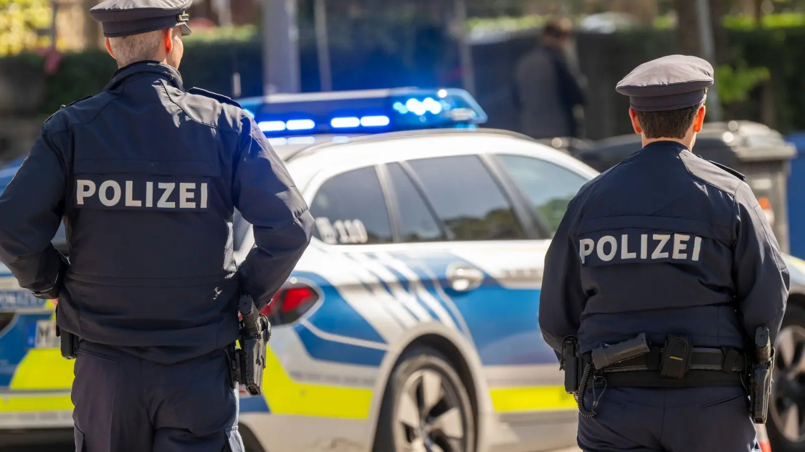 Polizisten stehen mit einem Streifenwagen am Haupteingang zum Oktoberfestgelände. (Archivbild) (Foto: Peter Kneffel/dpa)