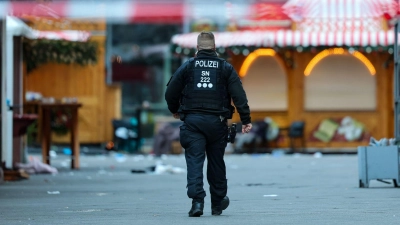 Ein Polizist geht hinter einer Absperrung am Magdeburger Weihnachtsmarkt.  (Foto: Jan Woitas/dpa)